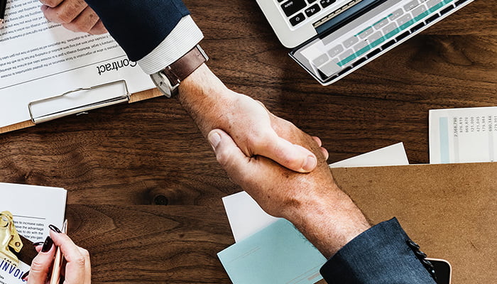 Two people shaking hands across a desk